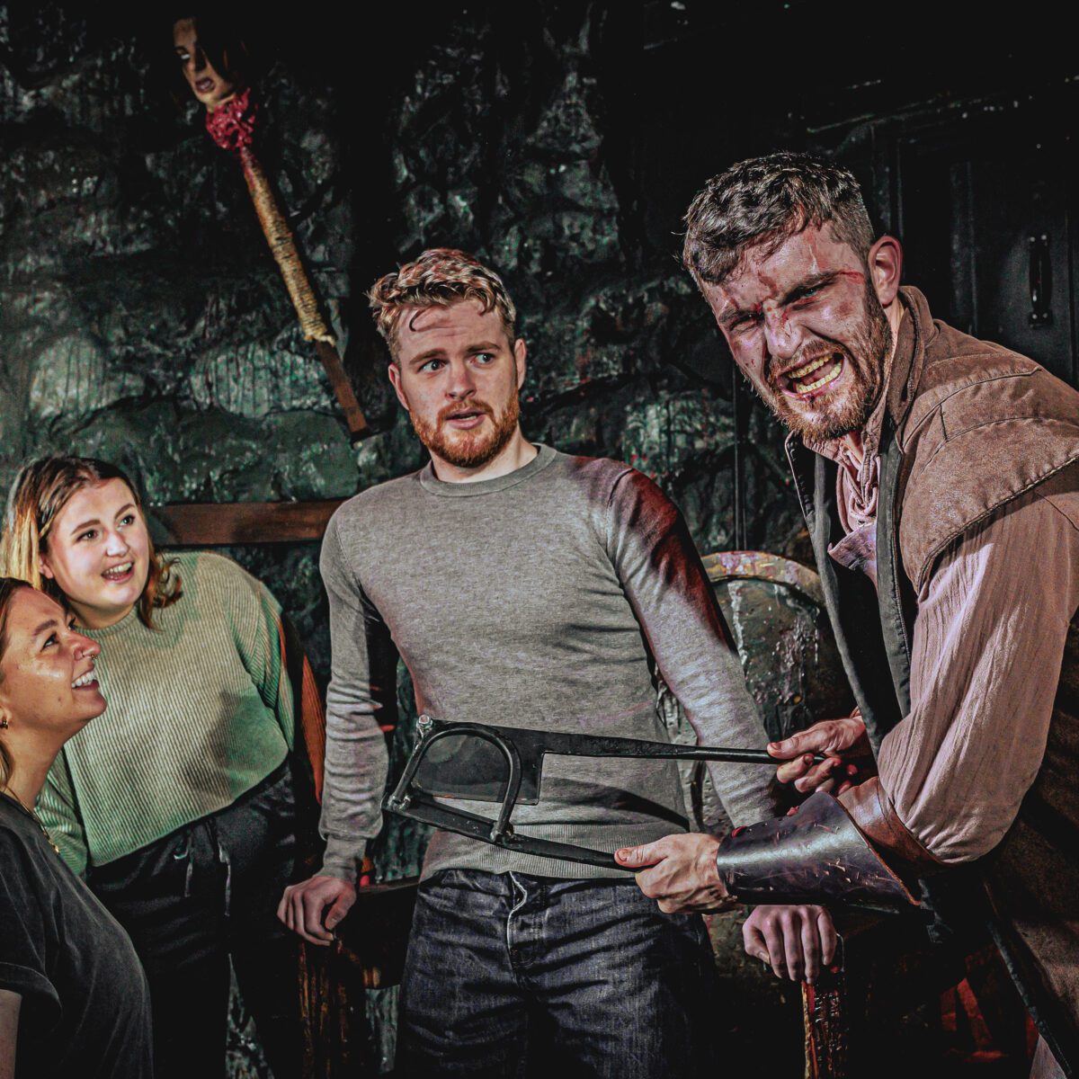 Two people looking frightened with an torturer at the London Dungeon